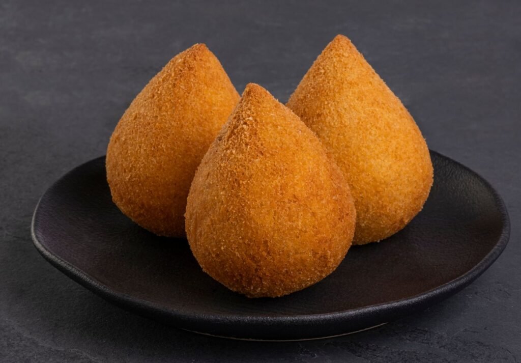 três coxinhas sobre um prato preto