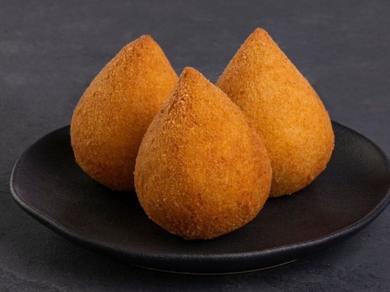 três coxinhas sobre um prato preto