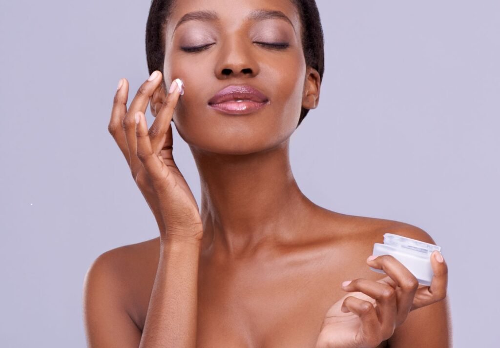 mulher negra aplicando creme para skincare no rosto