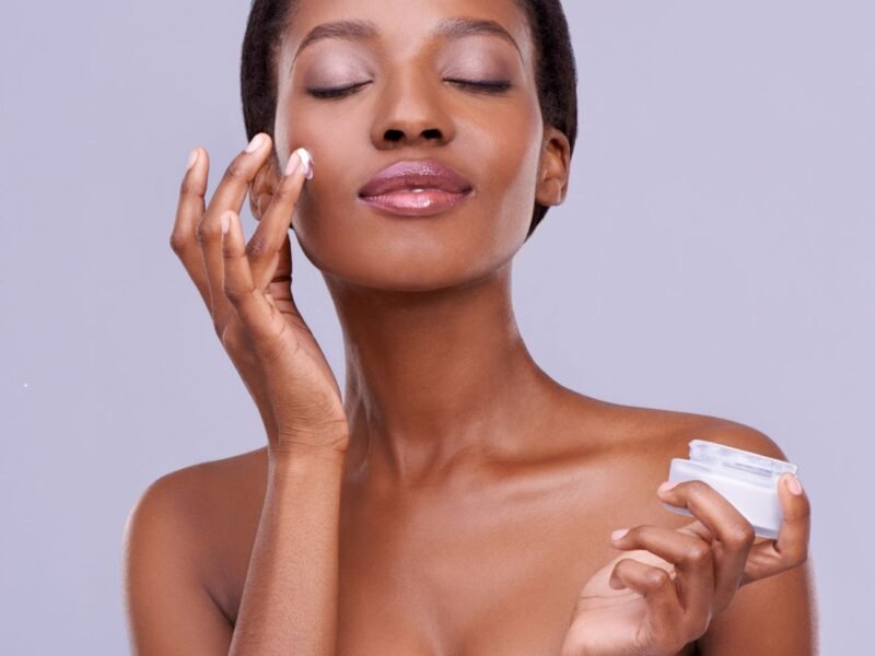 mulher negra aplicando creme para skincare no rosto